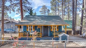 A small, single-story building with a porch and a small shed, surrounded by trees. - 'grizzly Pine' Cottage - Walk to Ski Beach Park! (Big Bear Lake)