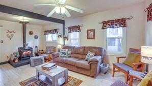 A cozy living room with a fireplace, leather sofa, and a ceiling fan. - 'grizzly Pine' Cottage - Walk to Ski Beach Park! (Big Bear Lake)