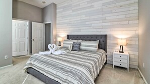 A bedroom with a bed, two nightstands, a wall-mounted lamp, and a door.