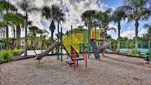 A playground with slides and climbing structures, surrounded by palm trees and a clear sky. - Kissimmee Retreat w/ Pool Access < 4 Mi to Disney! (Kissimmee)