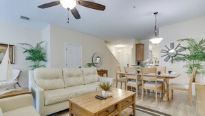 A living room with a sofa, coffee table, and dining area with chairs and a table. - Kissimmee Retreat w/ Pool Access < 4 Mi to Disney! (Kissimmee)