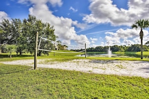 Ein Volleyballnetz in einem Park, im Hintergrund ein Springbrunnen und Bäume.