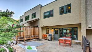 Een terras met stenen vloer, buitenzitplaatsen, een barbecue en een houten omheining.