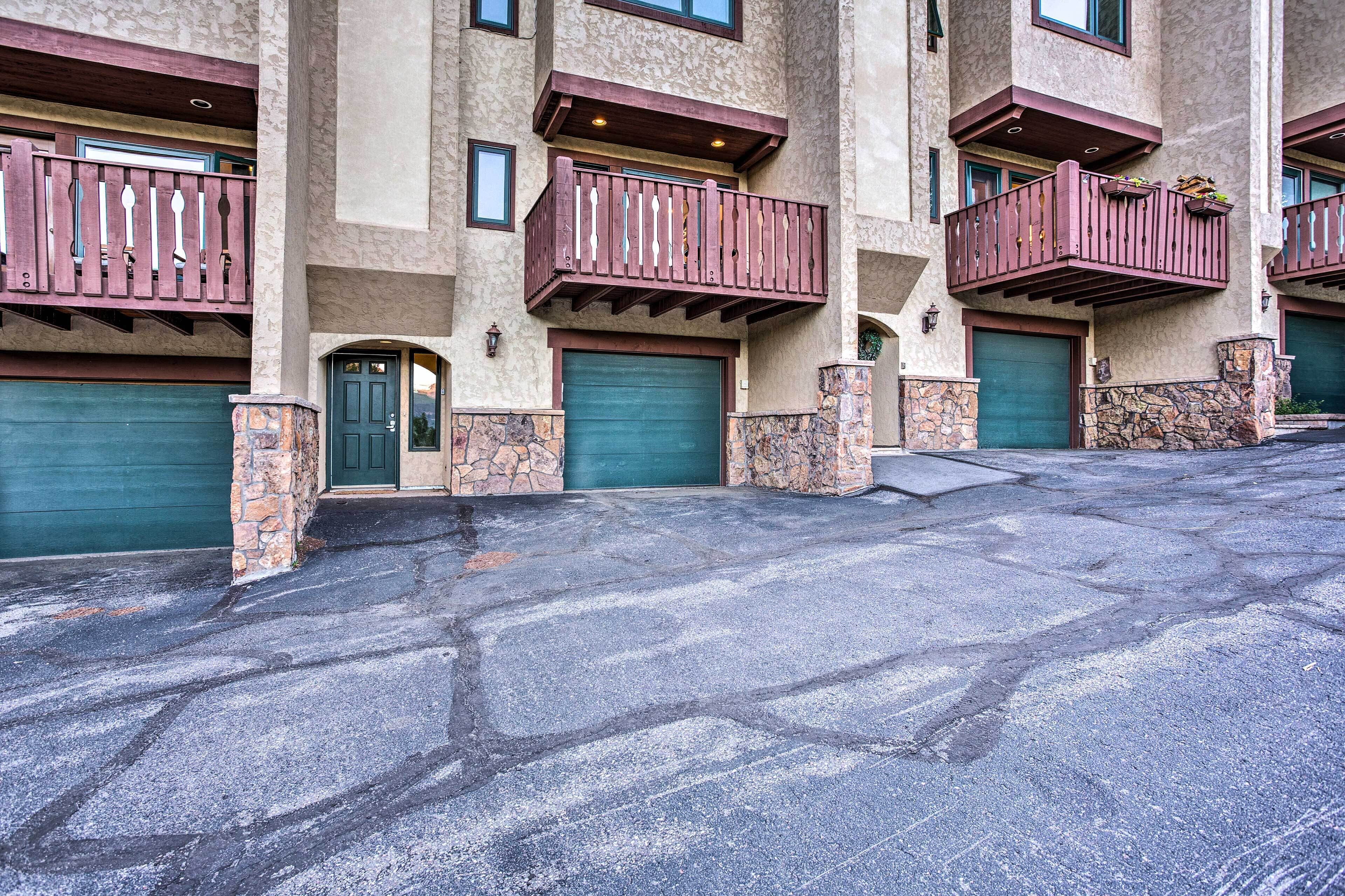 A multi-story building with balconies, stone pillars, and green garage doors.