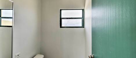 A small, narrow bathroom with a toilet, sink, and a small window.