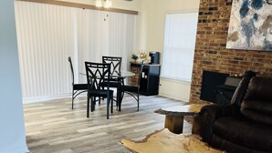 A living room with a wooden coffee table, a leather sofa, and a dining area with a table and chairs.