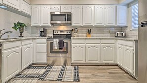 A kitchen with white cabinets, a microwave, an oven, and a toaster.