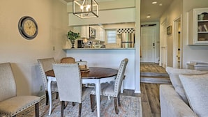 A dining area with a round table, four chairs, and a chandelier.