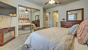 A bedroom with a bed, a ceiling fan, a TV, and a fish tank.