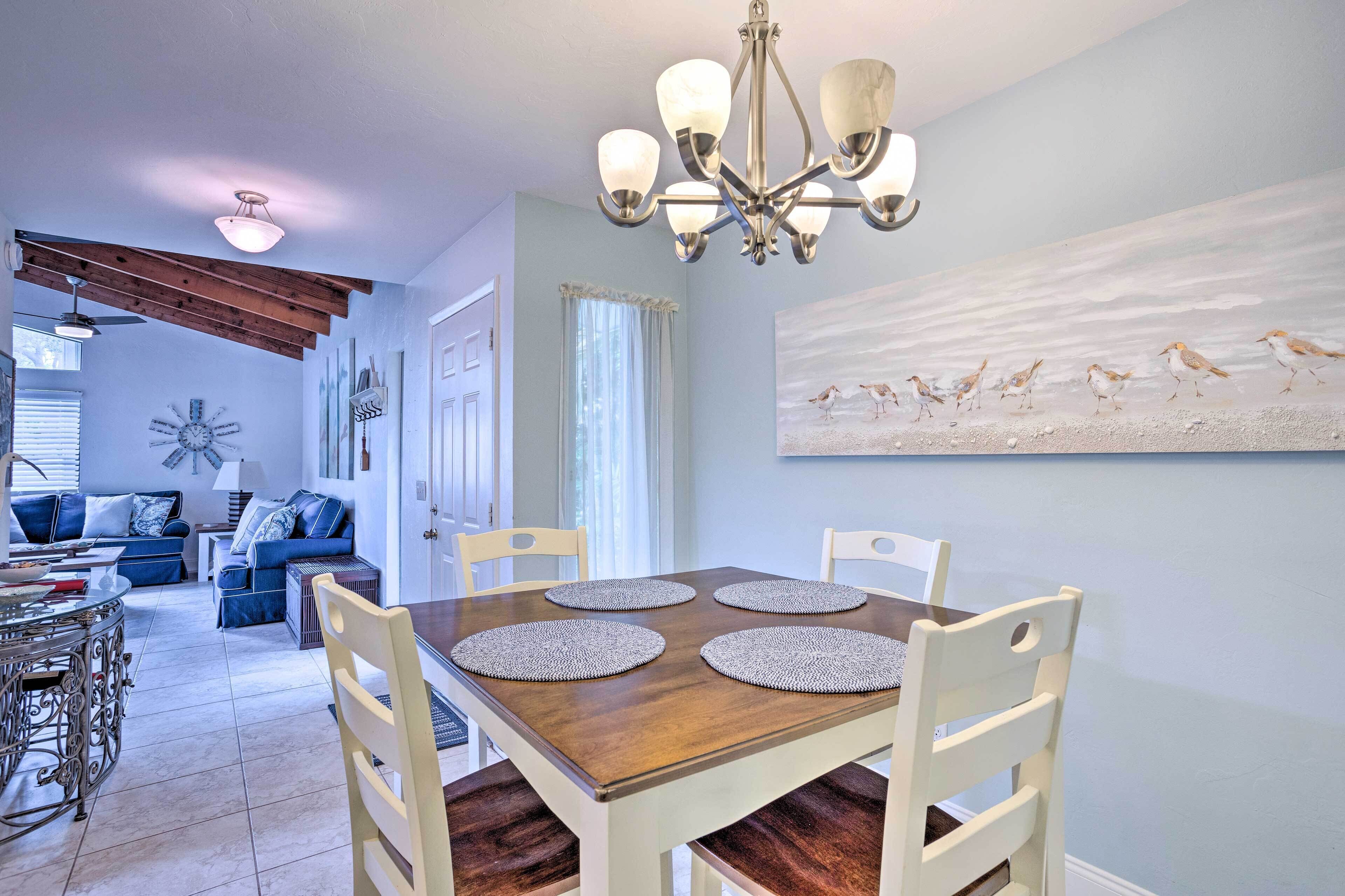 A dining area with a wooden table, white chairs, and a chandelier.