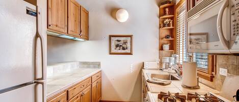 A kitchen with wooden cabinets, a refrigerator, a stove, and a sink.