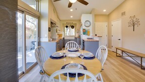 A dining area with a round table, white chairs, and blue placemats. There is a ceiling fan above and a clock on the wall. - 'roadrunner Roost' at Rams Hill Golf Resort! (Borrego Springs)
