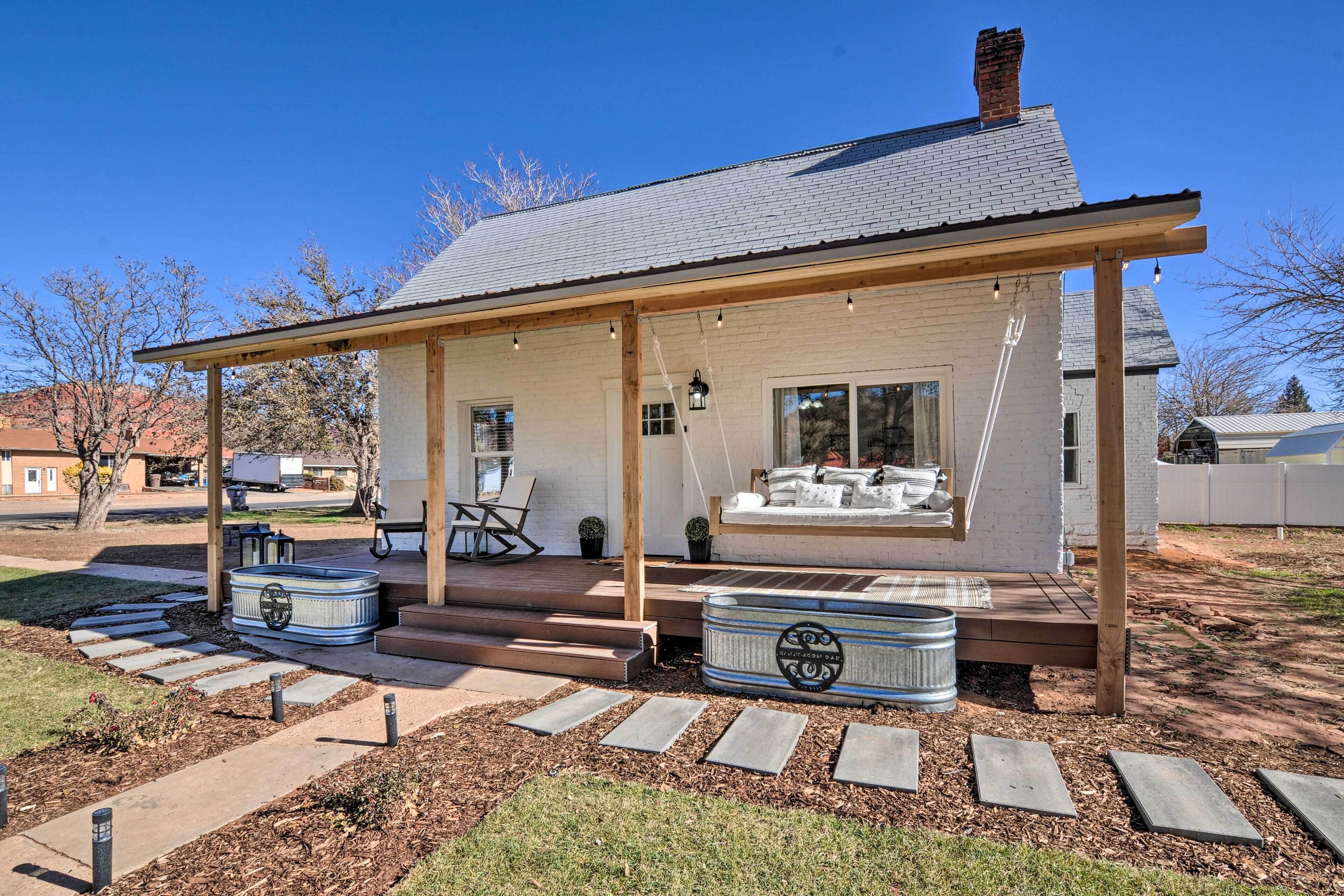 A house with a covered porch, outdoor seating, and two hot tubs.
