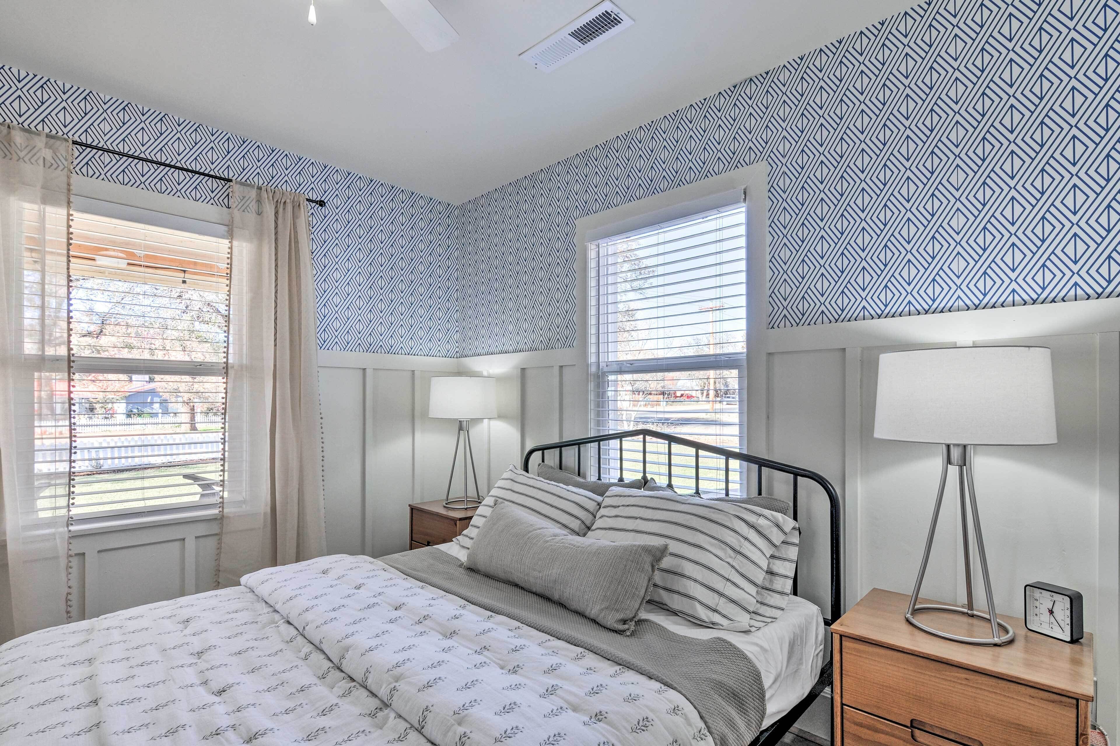 Une chambre à coucher avec un lit, deux tables de chevet, une lampe et une horloge.