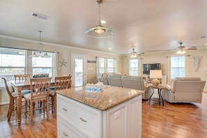 A spacious living area with a kitchen island, dining table, and seating.