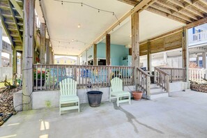 Un espace extérieur abrité, doté de poutres en bois, de deux chaises blanches et de plantes en pot.