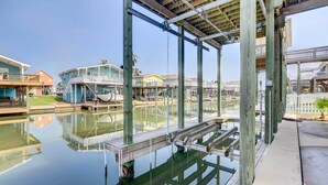 Ein Wohnhaus am Wasser mit einer Holzterrasse, einem überdachten Bereich und freiem Blick auf das Wasser.