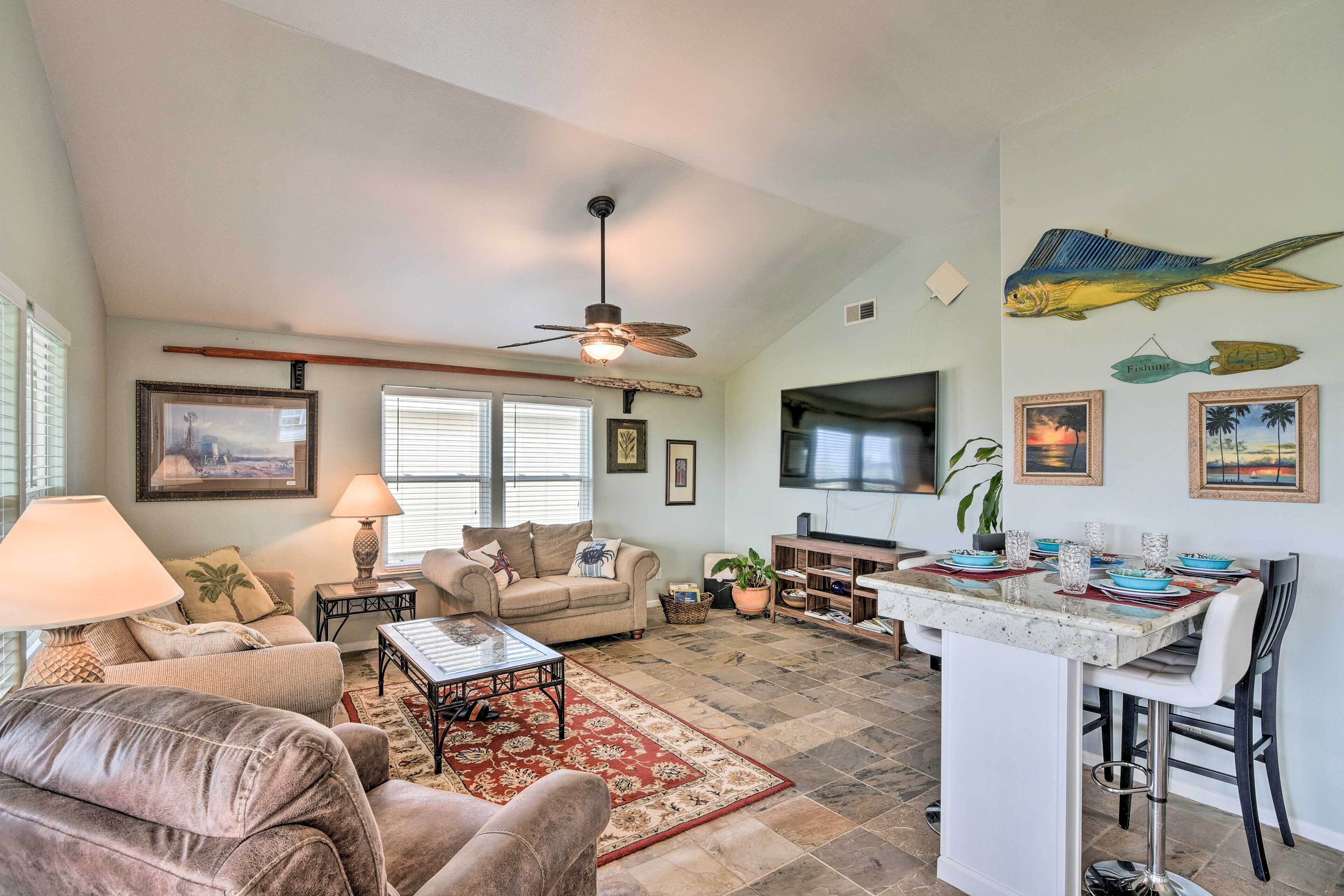 A spacious living area with a ceiling fan, a dining table with chairs, and a kitchen island.