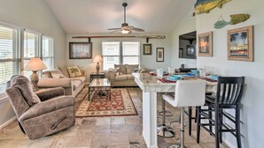 A spacious living area with a sofa, armchair, and a dining table with chairs. - Unwind Poolside, Walk to Beach! Galveston Retreat (Galveston)