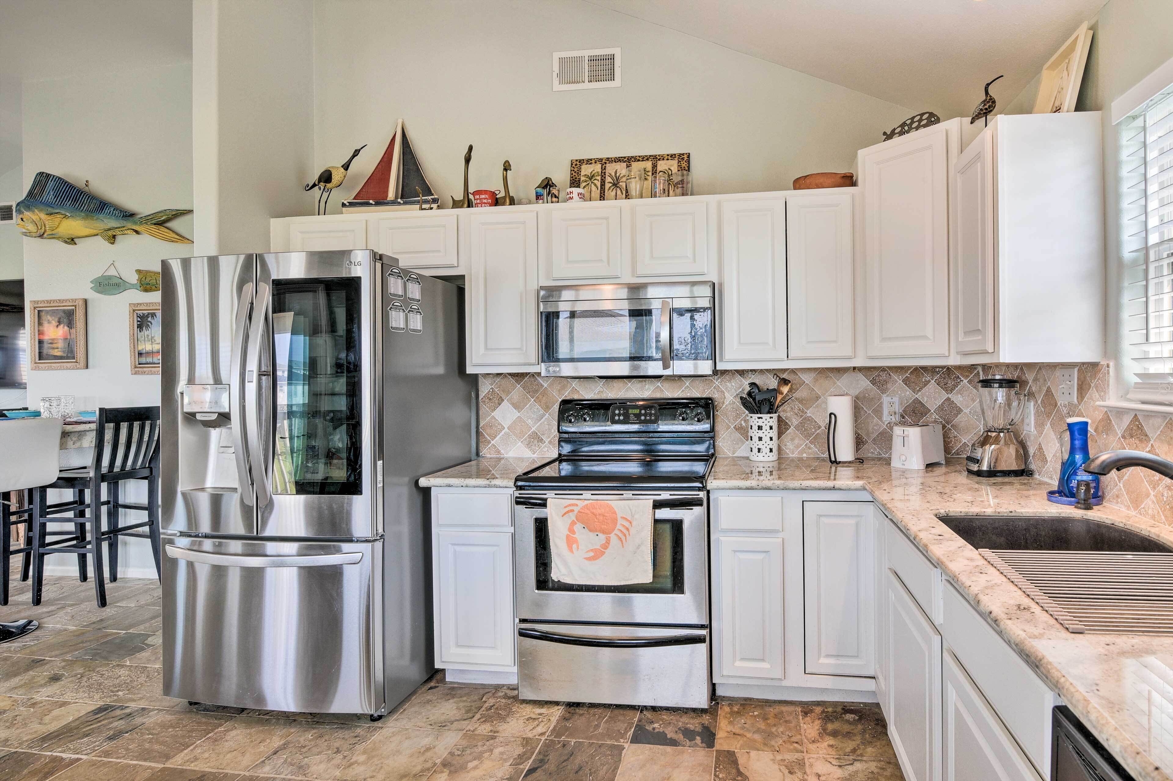 A kitchen with white cabinets, stainless steel appliances, a tiled backsplash, and a dining area with chairs.