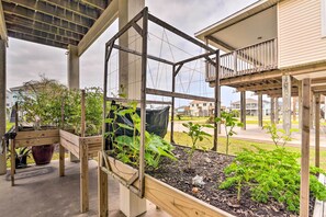 A wooden garden bed with various plants and a trellis structure. - Unwind Poolside, Walk to Beach! Galveston Retreat (Galveston)