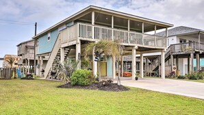 A two-story building with a balcony, a covered porch, and a small garden area with plants and a palm tree. - Unwind Poolside, Walk to Beach! Galveston Retreat (Galveston)