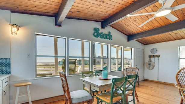 A dining area with a wooden ceiling, large windows, and a table with chairs. - Gulf Coast Views: Stilted Retreat in Galveston! (Galveston)