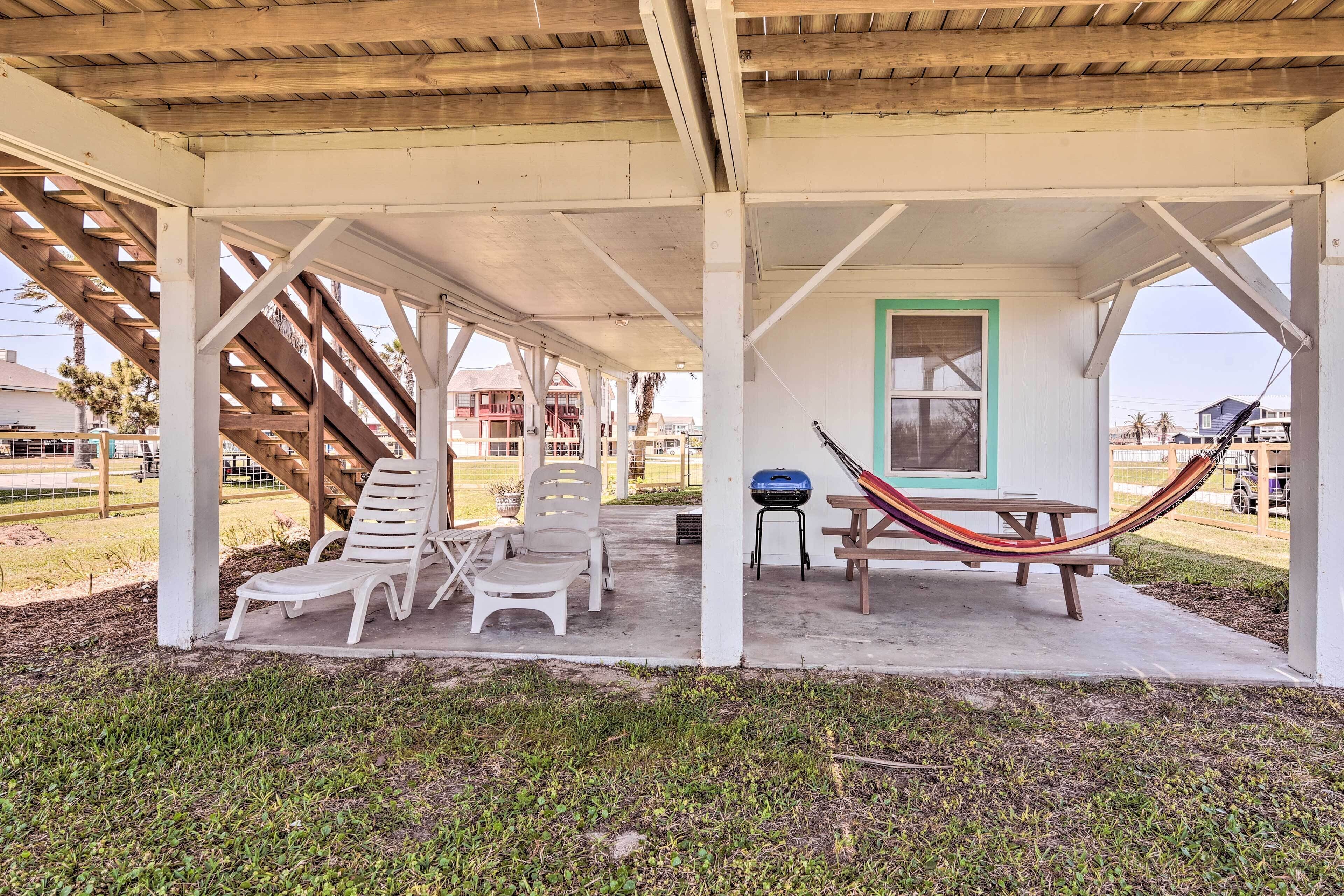 A covered outdoor area with white chairs and a hammock.