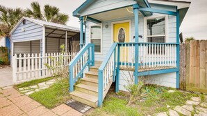 A small, single-story house with a porch, a garage, and a wooden fence.