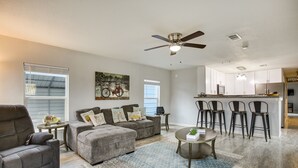 A spacious living room with a gray sofa, a coffee table, and a ceiling fan.