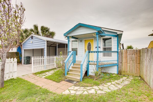 A small, single-story house with a blue exterior and a yellow door, featuring a front porch and a staircase leading to the entrance. - Galveston Cottage ~ 1 Mi to Beach: Pet Friendly! (Galveston)