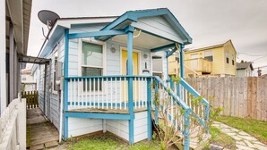 A small, single-story house with a blue porch and a wooden staircase leading to a front door.