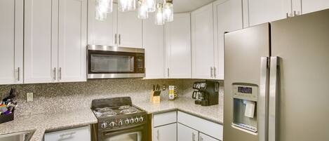 A modern kitchen with white cabinets, stainless steel appliances, and a built-in water dispenser.