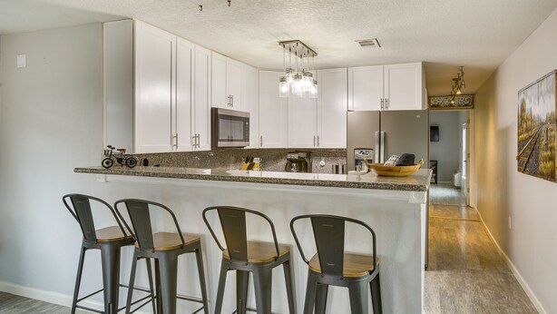 A modern kitchen with white cabinets, a granite countertop, and a central island with bar stools.