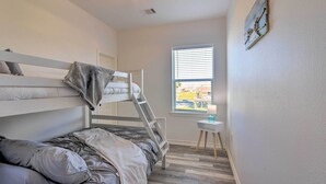 Ein Schlafzimmer mit Etagenbetten, einem kleinen Tisch und einem Fenster mit Jalousien.