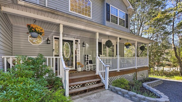 A two-story house with a covered porch, a welcome sign, and a doormat. - Poconos Escape w/ Hot Tub & Fire Pit (Albrightsville)