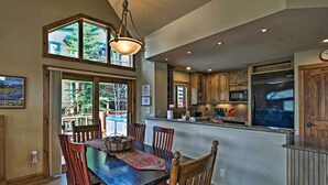 A spacious dining area with a wooden table and chairs, a chandelier, and large windows offering views of the outdoors. - Beautiful Breck Retreat: Walk to Gondola & Main St (Breckenridge)