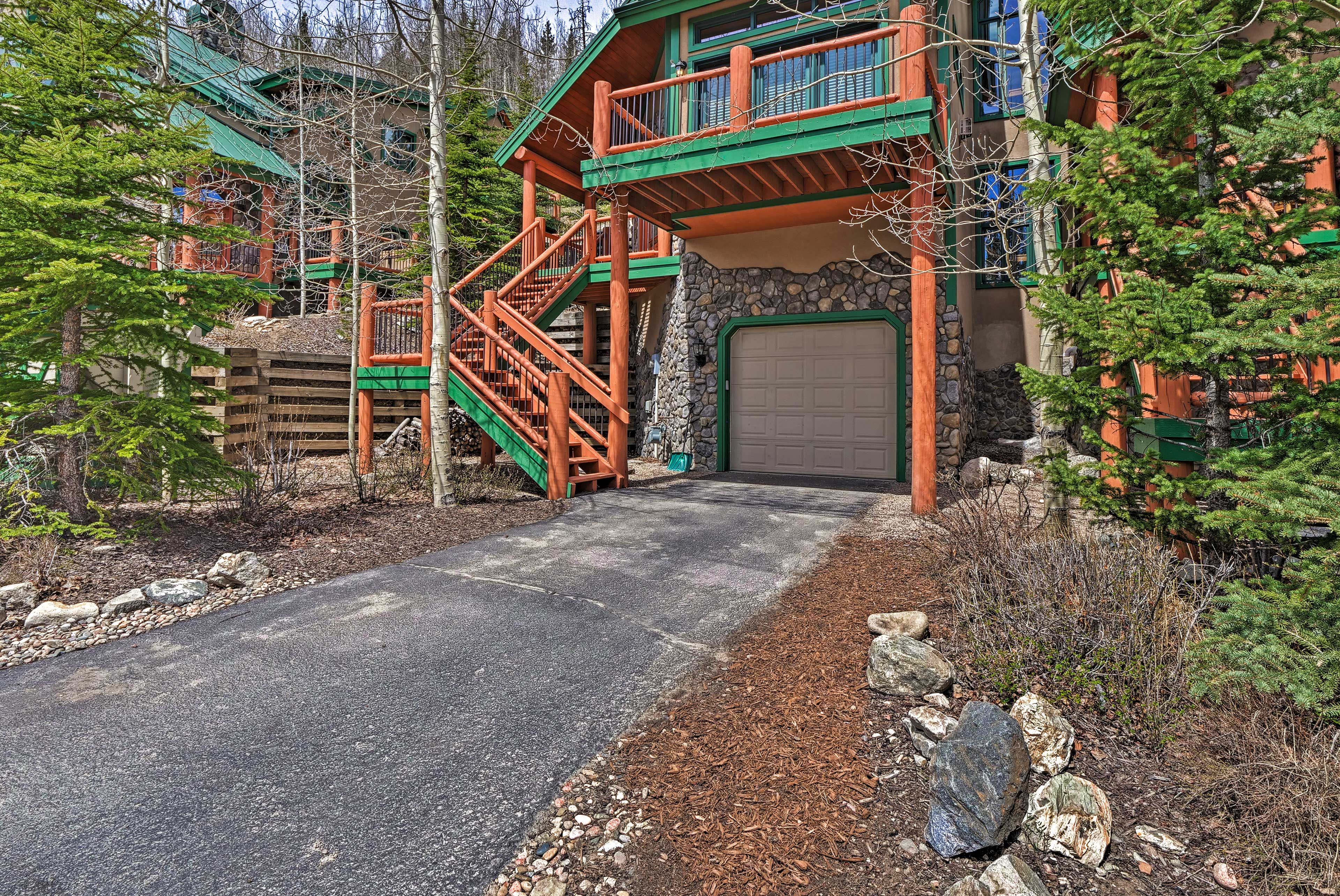 A multi-level wooden cabin with a stone foundation, a garage, and a wooden deck.