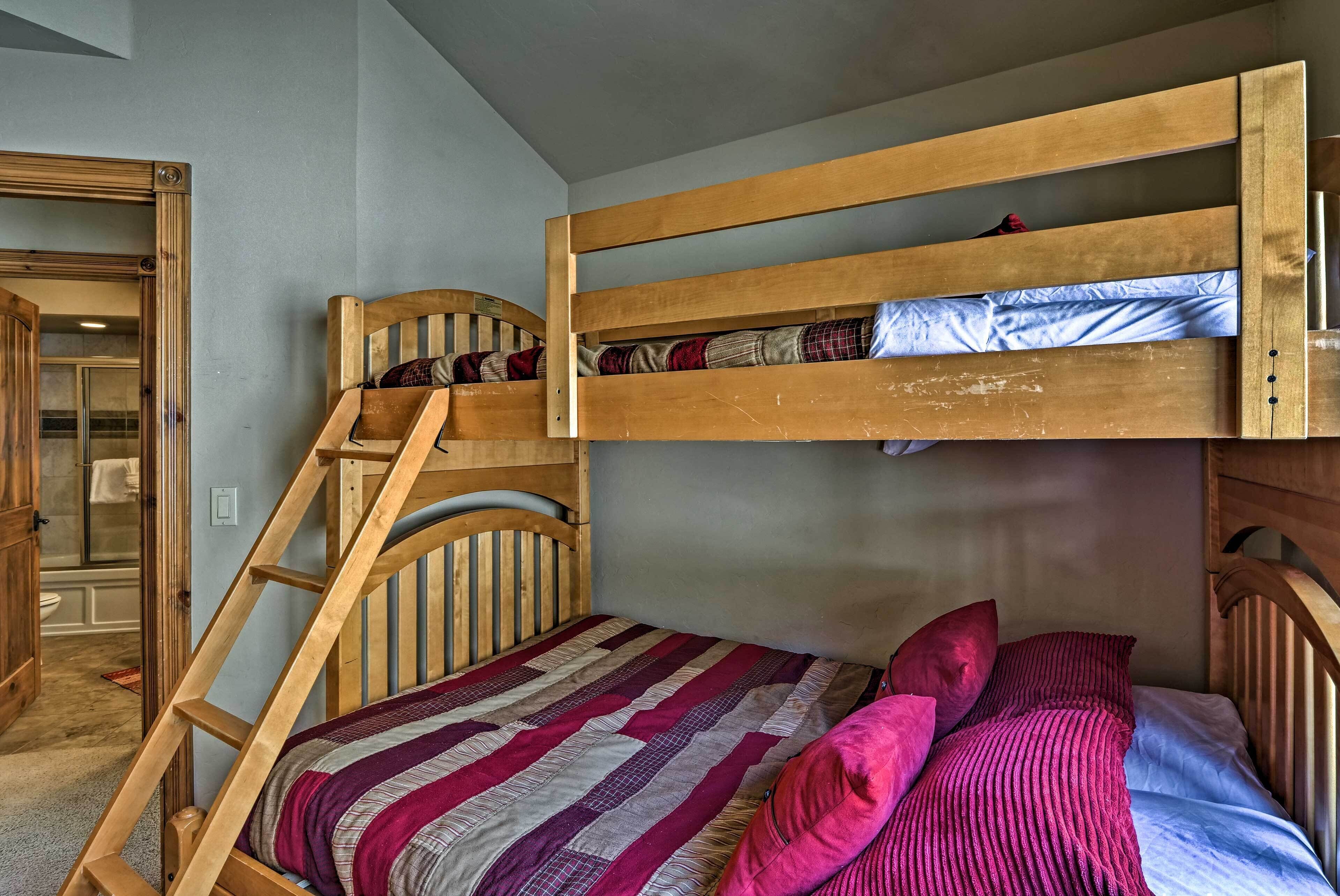 Een stapelbed met een houten ladder, een gestreept dekbedovertrek en roze kussens.