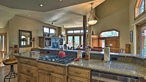A spacious kitchen with granite countertops, wooden cabinets, and a red kettle. - Beautiful Breck Retreat: Walk to Gondola & Main St (Breckenridge)