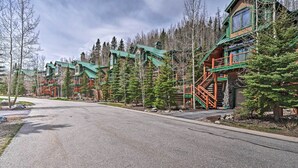 A row of log cabin-style buildings with a central staircase and a paved road in front. - Beautiful Breck Retreat: Walk to Gondola & Main St (Breckenridge)