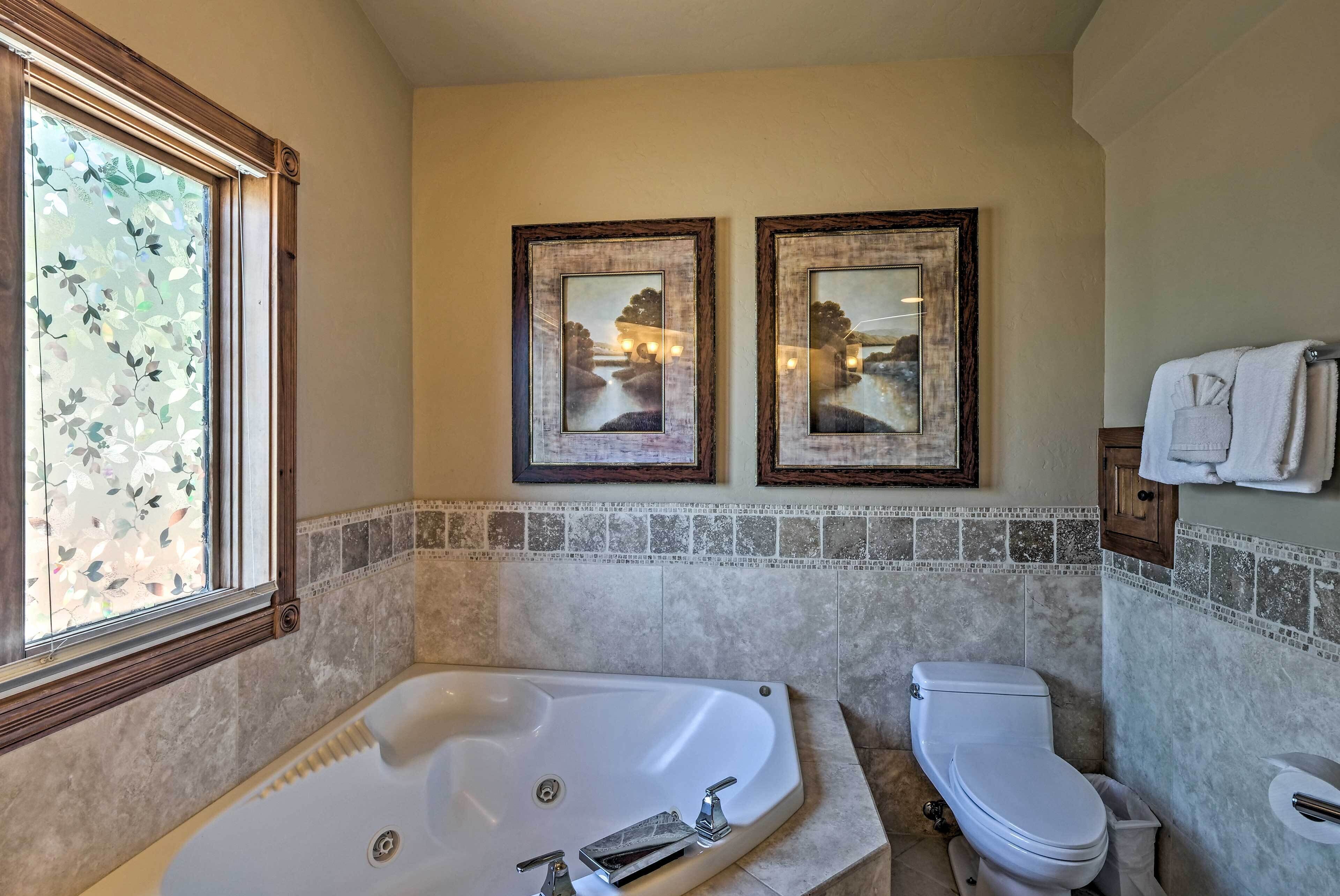 A bathroom with a bathtub, toilet, and two framed pictures on the wall.