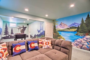 A room with a sofa, pillows, a painting of a mountain landscape, and a door. - 7 Mi to Rocky Mtn NP: Updated Estes Park Home (Estes Park)