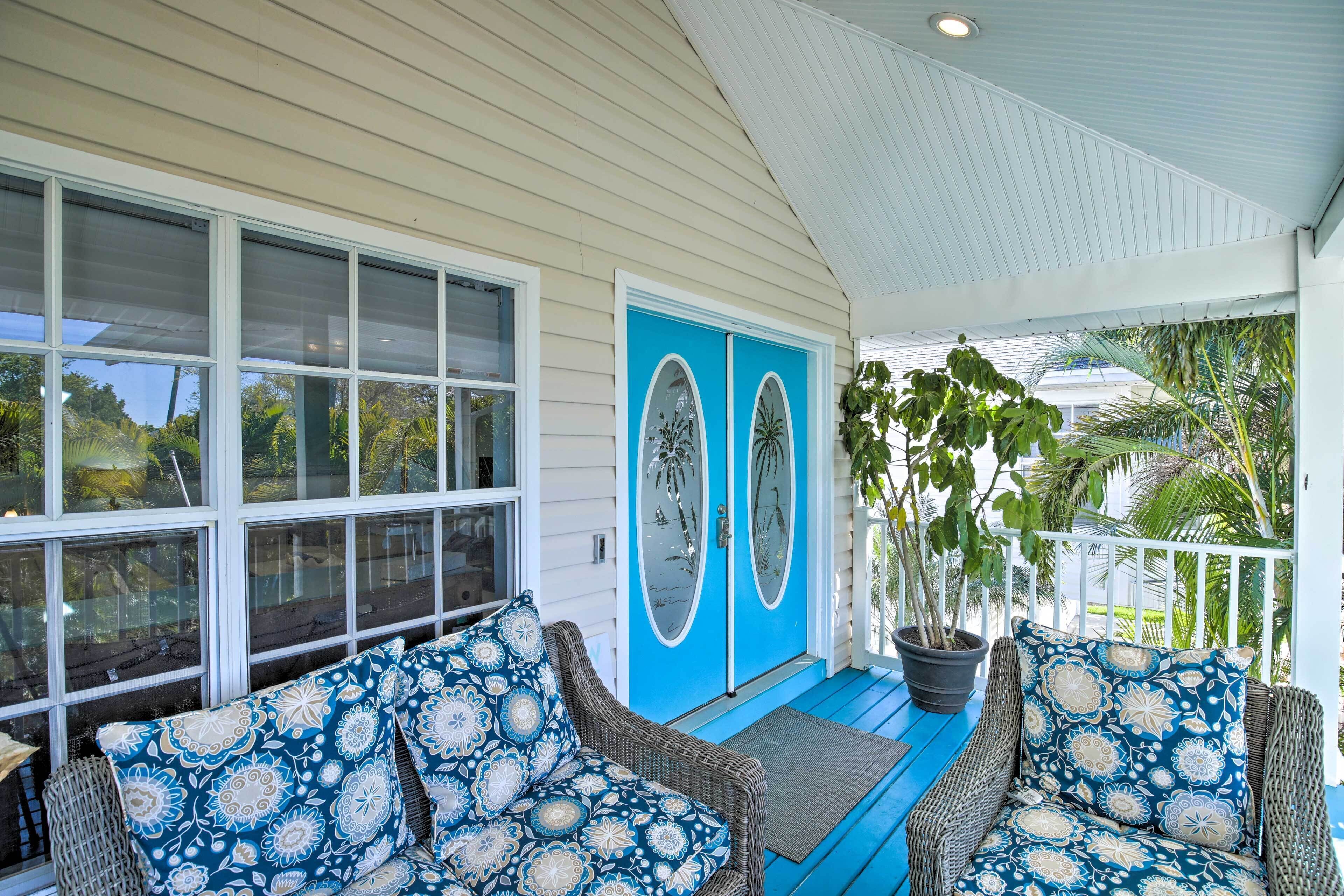 A covered porch with wicker furniture and a potted plant.