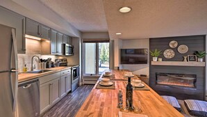 Une cuisine moderne avec des meubles gris, un plan de travail en bois, un four encastré et une cheminée.