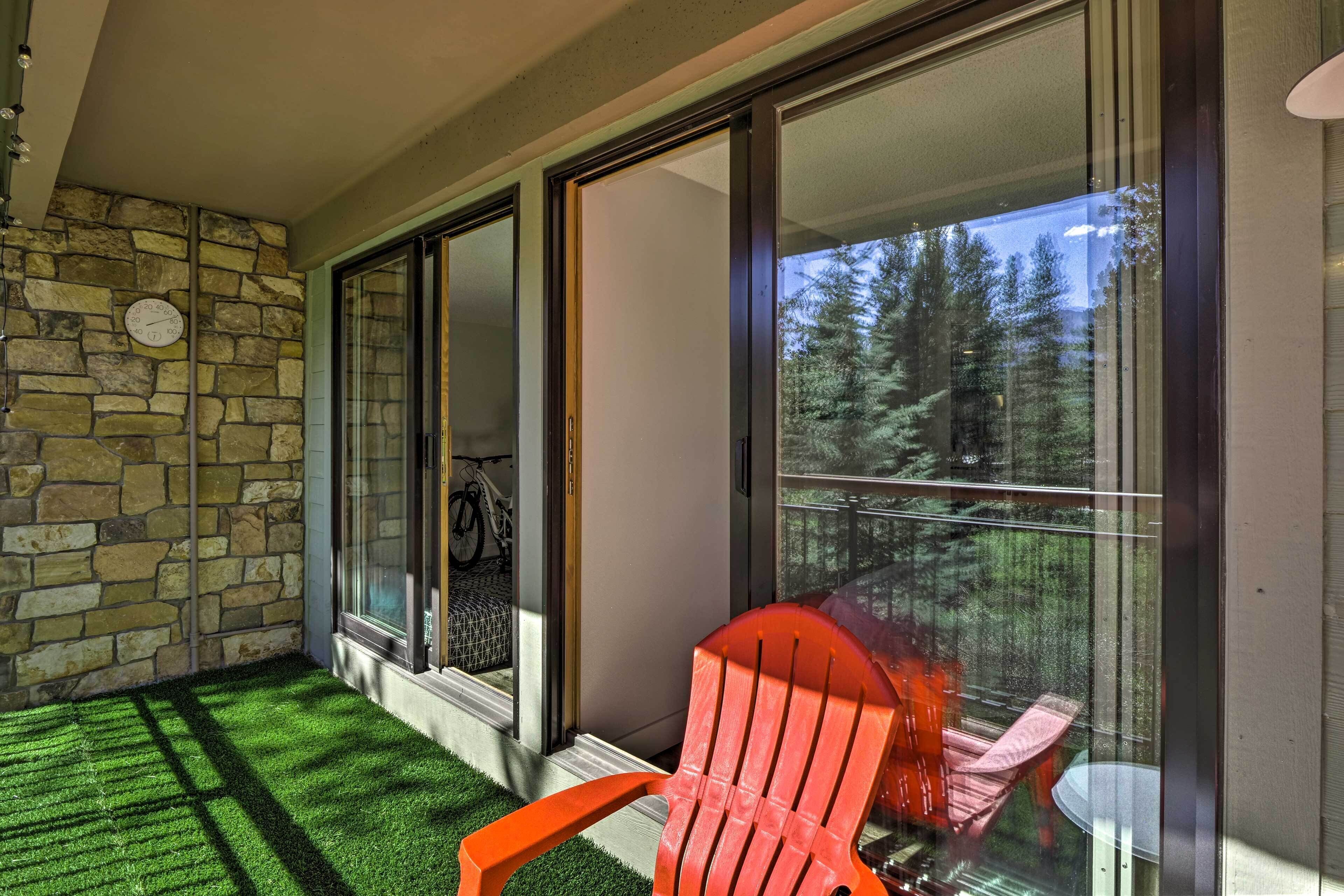 A balcony with a stone wall, sliding glass doors, and a red chair.