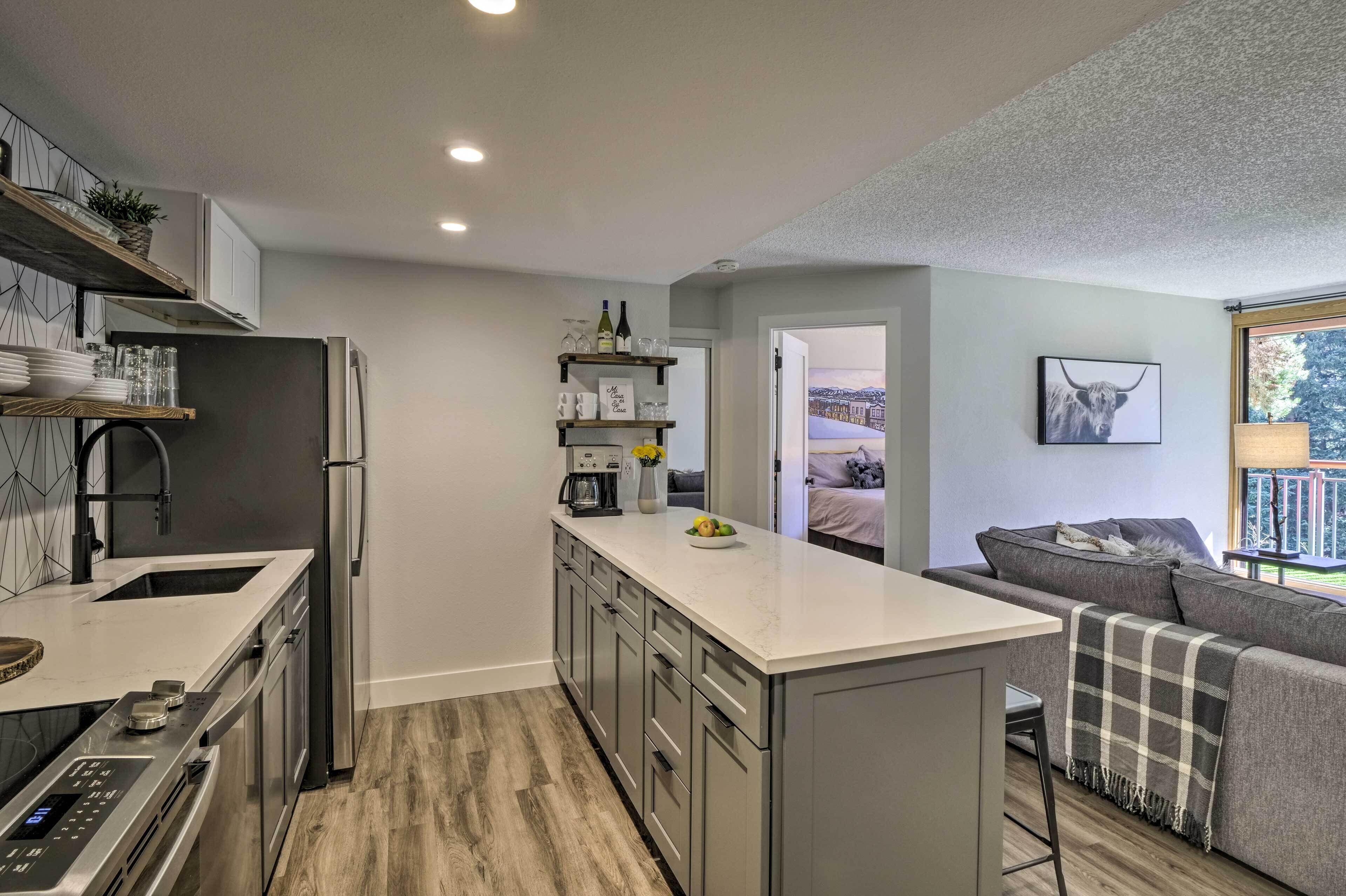 A modern kitchen with a central island, built-in appliances, and a view to a balcony.