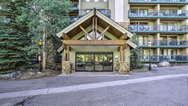 A building with a wooden entrance, stone pillars, and a balcony with railings. - Walk to Main St & Ski Lift: Breck Condo w/ Pool! (Breckenridge)