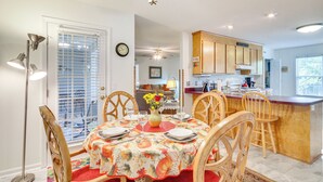 A dining area with a table set for four, wooden chairs, a vase with flowers, and a ceiling fan. - Chapin Home Near Boat Launch & Lake Murray! (Chapin)