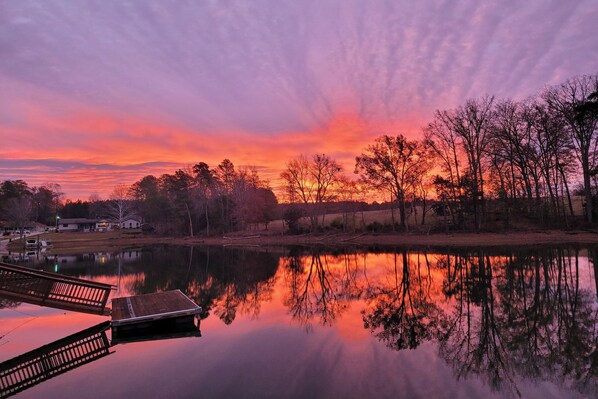 A serene lakeside scene with a dock extending into the water, surrounded by trees and a sunset sky. - Chapin Home Near Boat Launch & Lake Murray! (Chapin)